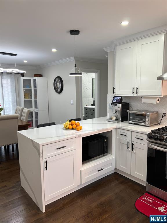 kitchen with pendant lighting, kitchen peninsula, gas stove, and white cabinets