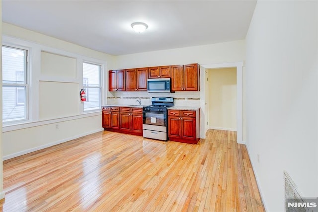 kitchen featuring light wood-type flooring, appliances with stainless steel finishes, backsplash, and sink