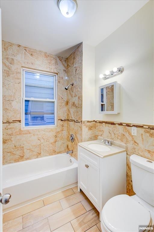 full bathroom featuring vanity, tiled shower / bath combo, tile walls, tile patterned flooring, and toilet