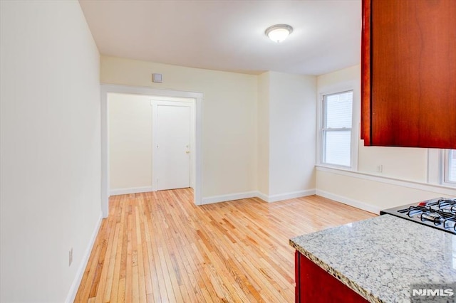 kitchen featuring light stone counters, light hardwood / wood-style flooring, and range