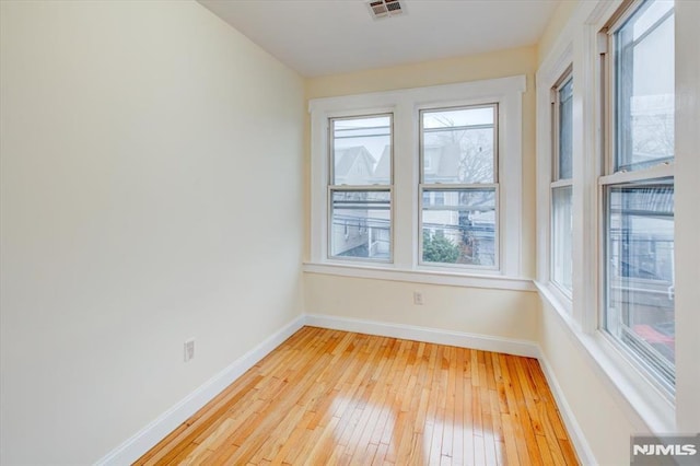 unfurnished room featuring a healthy amount of sunlight and light wood-type flooring