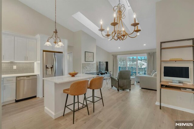 kitchen featuring hanging light fixtures, stainless steel appliances, tasteful backsplash, a breakfast bar area, and white cabinets