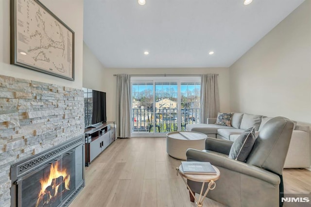 living room with light wood-type flooring and a stone fireplace