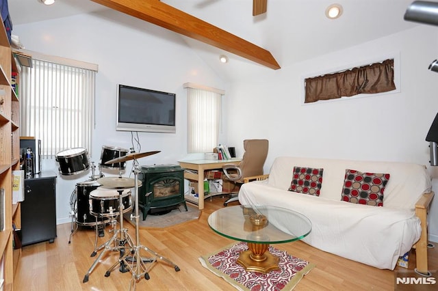 living room featuring a wood stove, hardwood / wood-style floors, and vaulted ceiling with beams