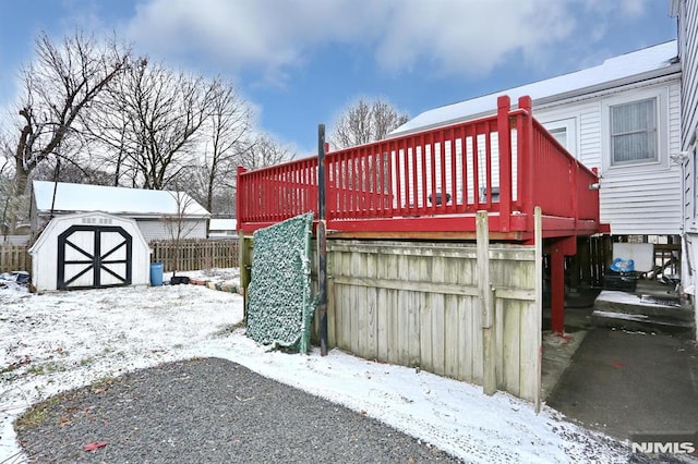 snowy yard with a deck and a shed