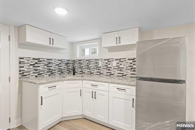 kitchen featuring stainless steel fridge, sink, and white cabinets