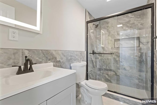 bathroom featuring an enclosed shower, vanity, toilet, and tile walls