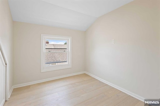 unfurnished room featuring vaulted ceiling and light wood-type flooring