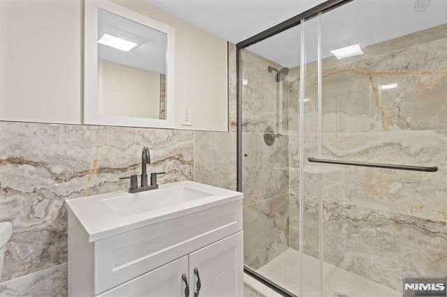 bathroom with vanity, tile walls, and a shower with shower door