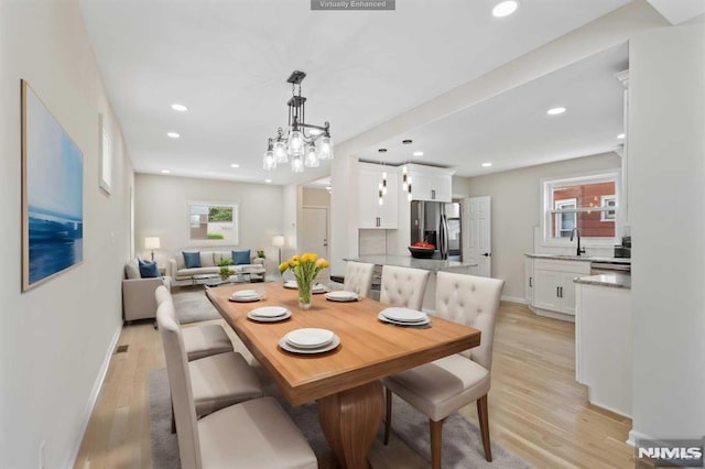 dining space featuring sink, light hardwood / wood-style floors, and an inviting chandelier