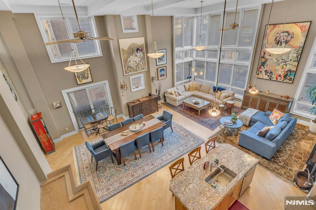 sitting room with ceiling fan, a towering ceiling, and light wood-type flooring