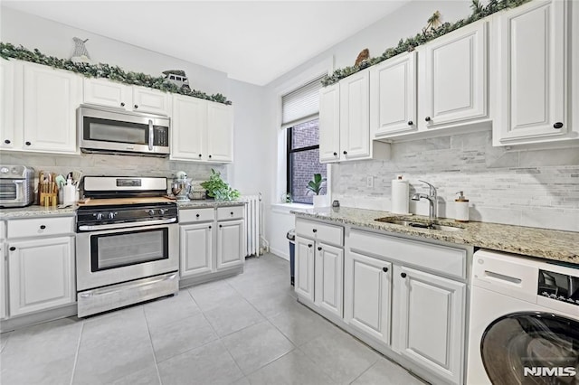 kitchen featuring white cabinets, sink, appliances with stainless steel finishes, and washer / dryer