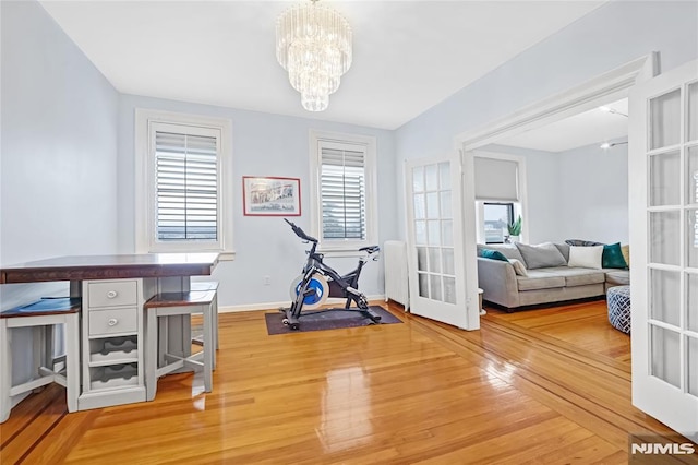 workout room featuring wood-type flooring, french doors, and a chandelier