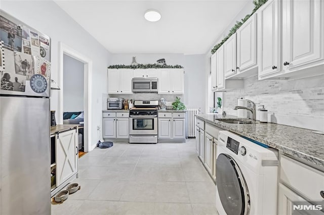 kitchen with washer / dryer, white cabinetry, appliances with stainless steel finishes, and sink