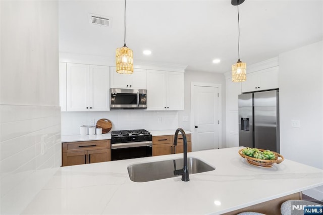 kitchen featuring white cabinetry, appliances with stainless steel finishes, sink, and pendant lighting