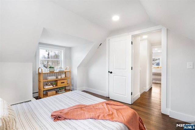 bedroom with dark hardwood / wood-style floors, vaulted ceiling, and a baseboard heating unit