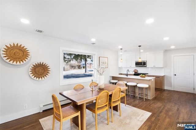 dining room featuring a baseboard radiator, sink, and dark hardwood / wood-style flooring