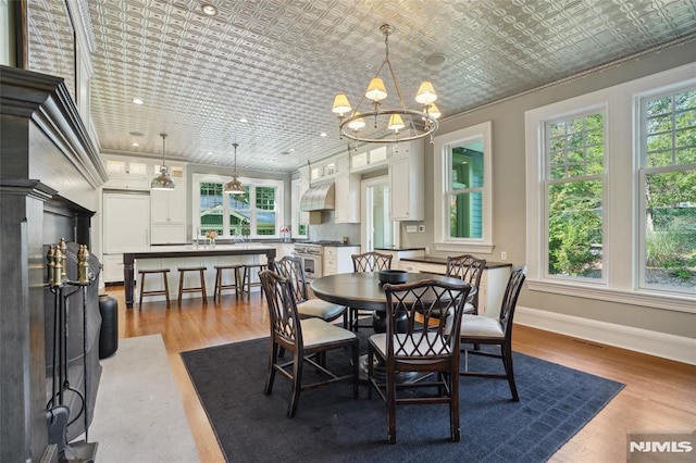 dining room featuring a healthy amount of sunlight, light hardwood / wood-style floors, and a notable chandelier