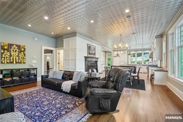 living room featuring light wood-type flooring, an inviting chandelier, and ornamental molding