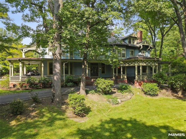 back of house featuring a lawn and covered porch