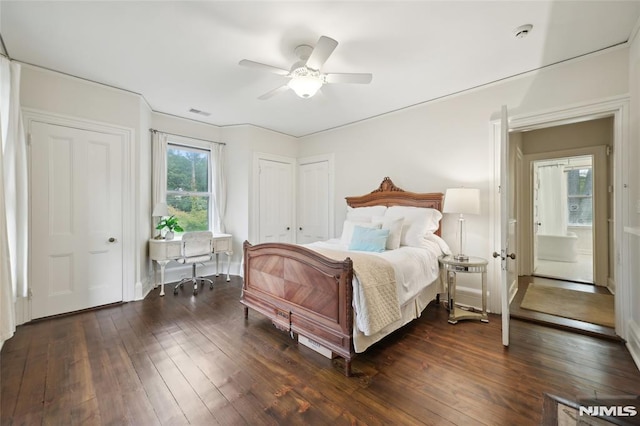 bedroom with multiple closets, ceiling fan, and dark wood-type flooring