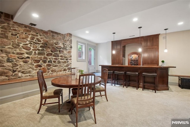 dining room featuring light carpet and indoor bar