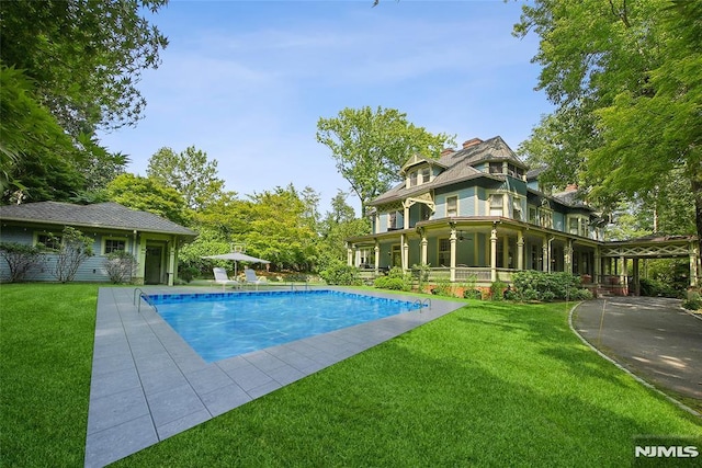 view of swimming pool with a patio area, ceiling fan, and a yard