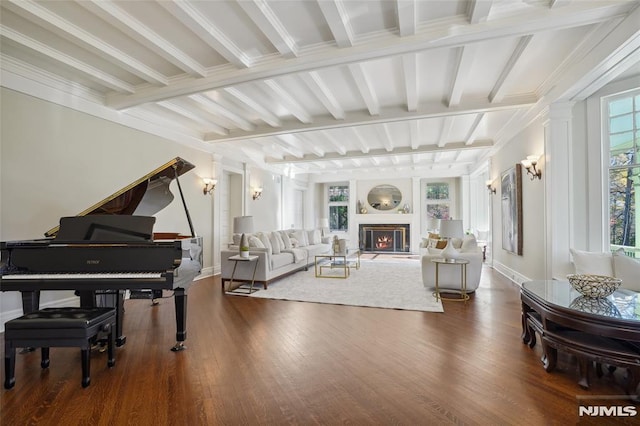 living room featuring beamed ceiling, dark hardwood / wood-style flooring, decorative columns, and ornamental molding