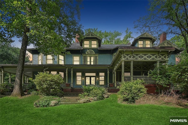 back of property featuring a lawn and covered porch