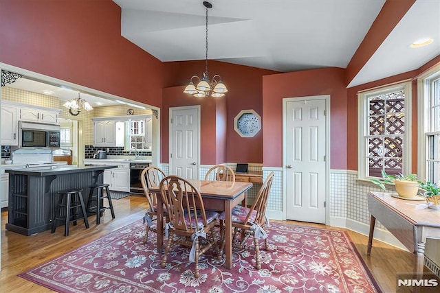 dining room with sink, light wood-type flooring, and an inviting chandelier