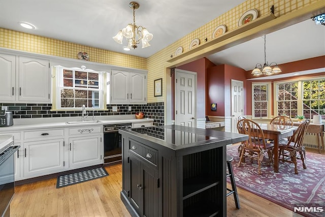 kitchen featuring a notable chandelier, black dishwasher, white cabinetry, and decorative light fixtures