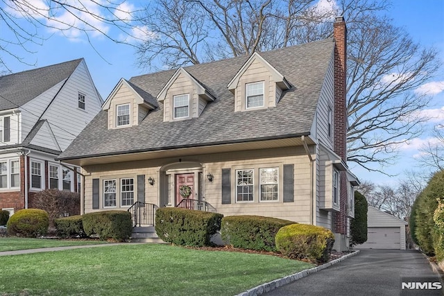 cape cod home with an outbuilding, a front yard, and a garage