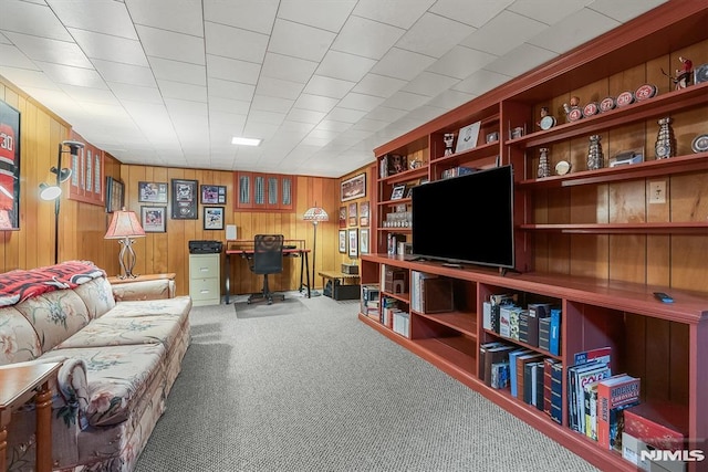 carpeted office featuring wooden walls and built in shelves