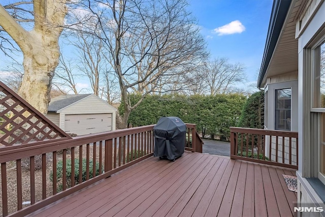 wooden deck featuring area for grilling, a garage, and an outbuilding