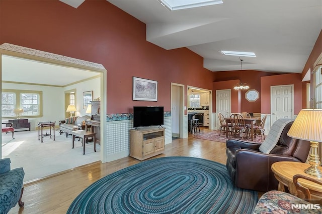 living room with lofted ceiling, an inviting chandelier, and light hardwood / wood-style flooring