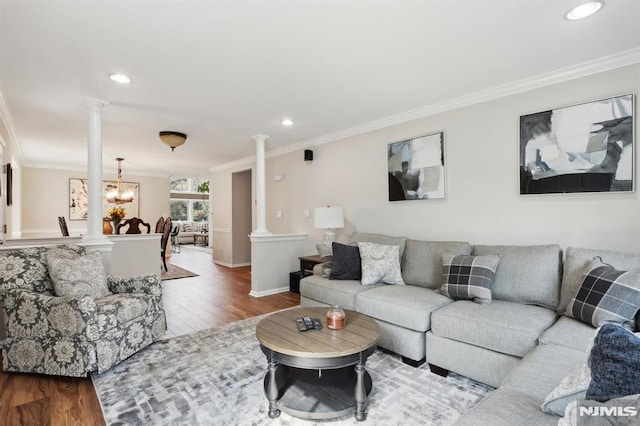 living room with hardwood / wood-style flooring, crown molding, a chandelier, and ornate columns