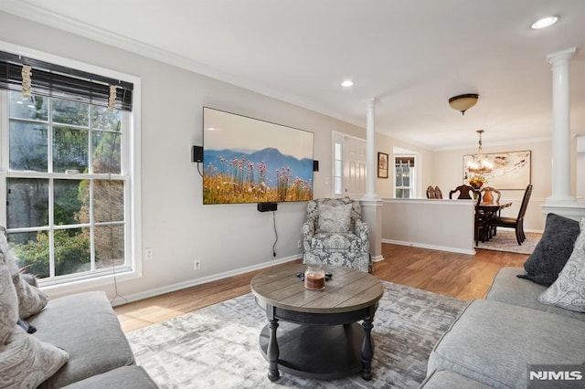 living room featuring decorative columns, a healthy amount of sunlight, and a notable chandelier