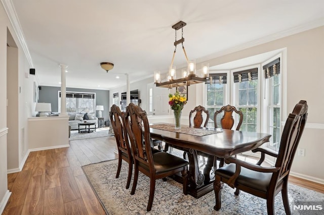 dining space with ornamental molding, light hardwood / wood-style flooring, a healthy amount of sunlight, and ornate columns