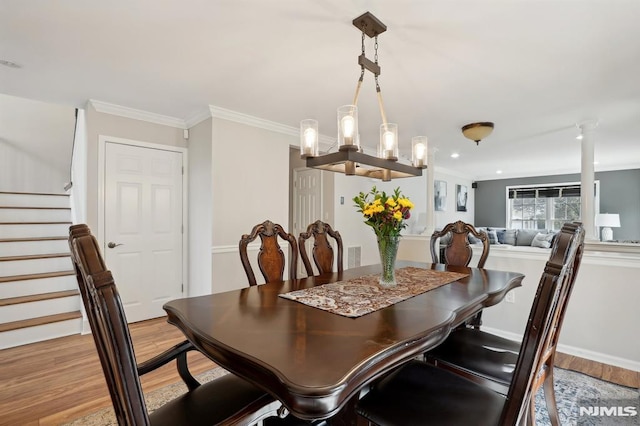 dining room with light wood-type flooring, ornamental molding, and a chandelier