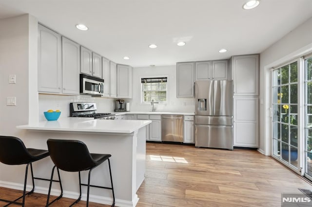 kitchen with stainless steel appliances, a wealth of natural light, backsplash, and kitchen peninsula