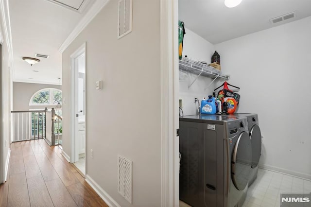 laundry area featuring washer and dryer, light hardwood / wood-style floors, and crown molding