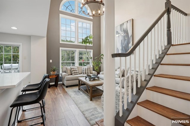 stairway featuring hardwood / wood-style floors, a towering ceiling, and a chandelier