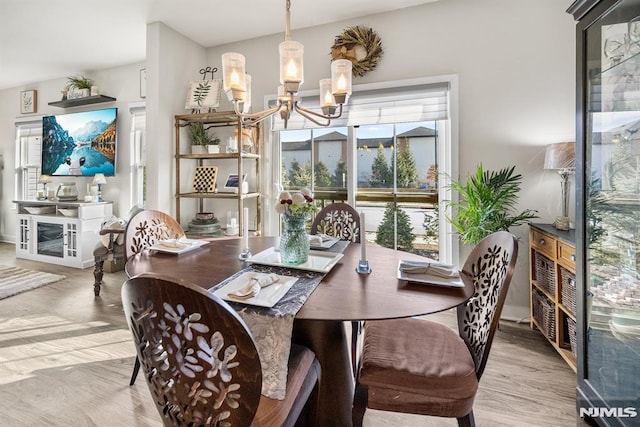 dining area with light hardwood / wood-style flooring and an inviting chandelier