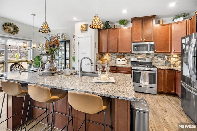 kitchen featuring pendant lighting, sink, decorative backsplash, appliances with stainless steel finishes, and light hardwood / wood-style floors