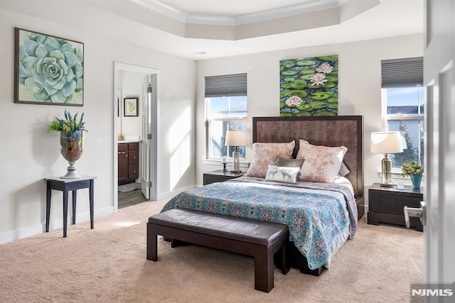 bedroom featuring ornamental molding, light carpet, connected bathroom, and a tray ceiling