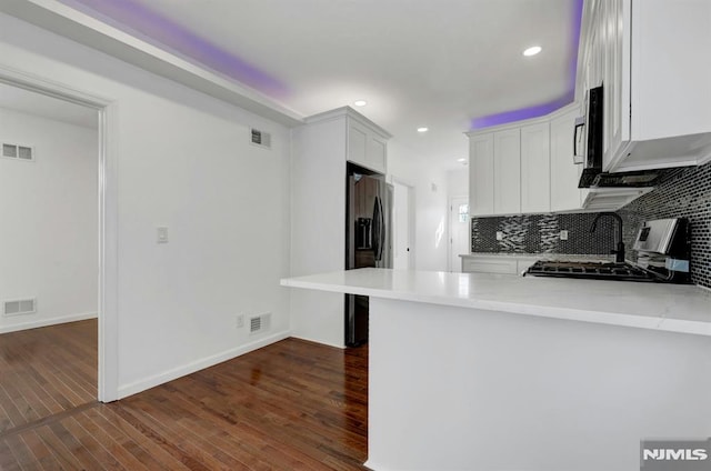 kitchen with kitchen peninsula, a kitchen breakfast bar, stove, black fridge with ice dispenser, and white cabinets