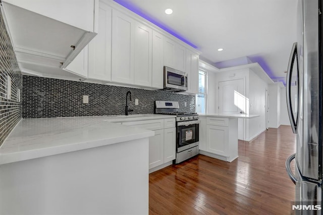 kitchen with appliances with stainless steel finishes, white cabinetry, sink, backsplash, and light stone counters