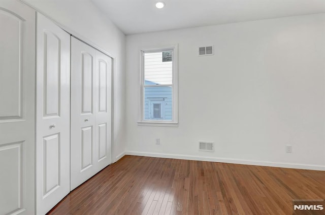 unfurnished bedroom featuring a closet and dark wood-type flooring