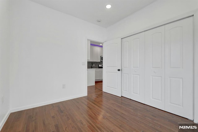 unfurnished bedroom featuring dark wood-type flooring, a closet, and sink