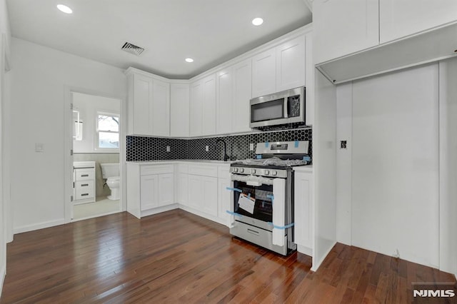 kitchen featuring backsplash, white cabinetry, dark hardwood / wood-style floors, and stainless steel appliances